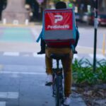 Trabajador de PedidosYa circula en bicicleta por una calle de La Plata