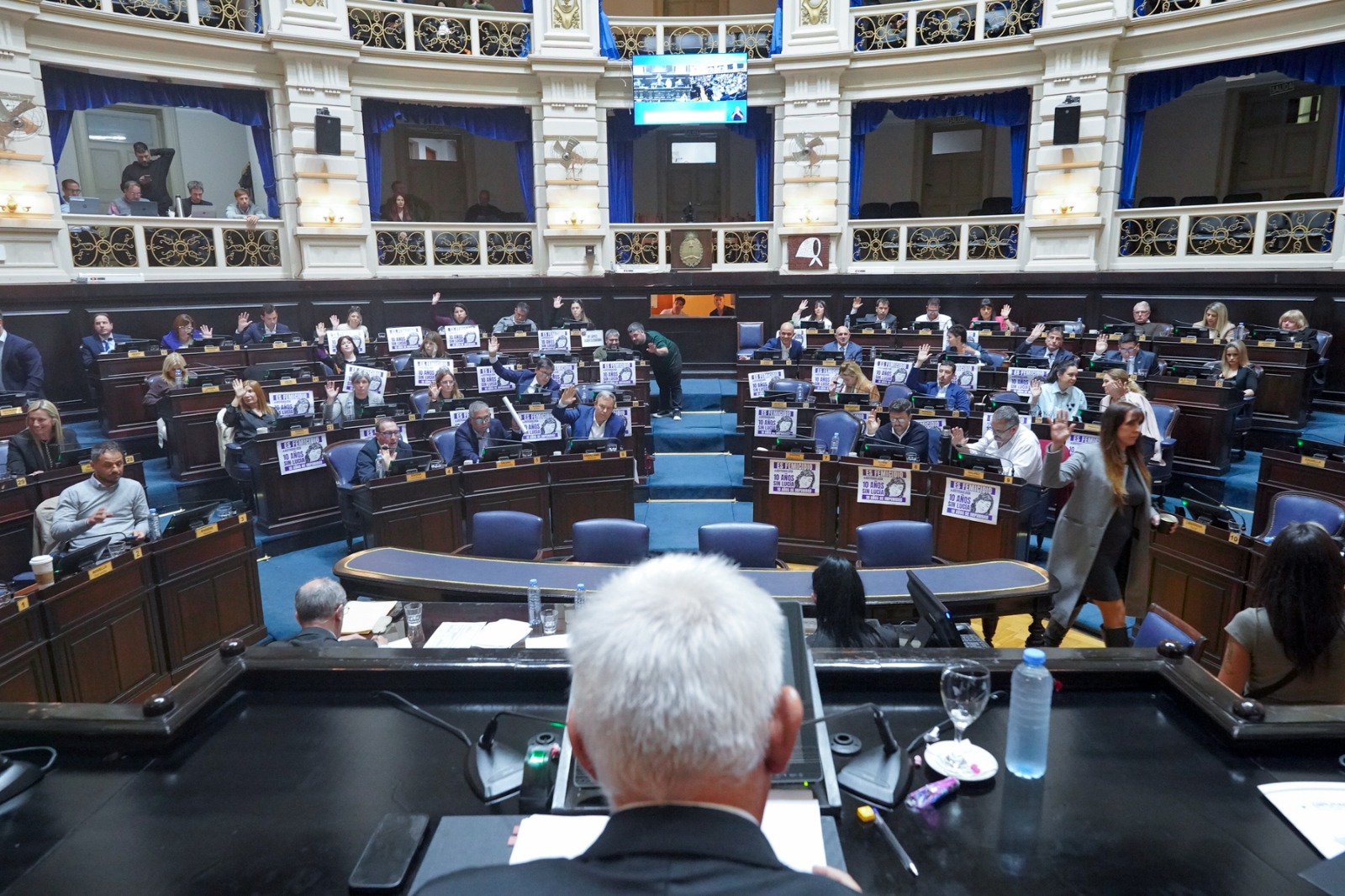 Diputados bonaerenses levantan la mano durante la votación de proyectos sobre sobreendeudamiento